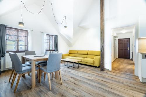 a living room with a yellow couch and a table and chairs at Residence Wurmfeld - Rodinný apartmán s 3 ložnicemi in Český Krumlov