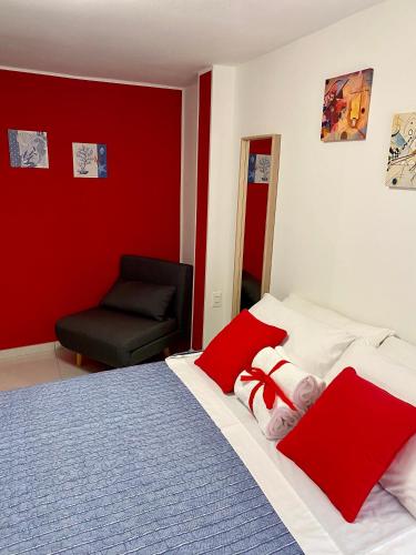 a bedroom with two beds with red walls and a chair at LAGUNA BLU Camera TRAMONTO con terrazza panoramica in comune in Chioggia