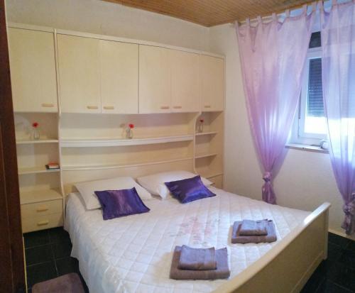 a bedroom with a large white bed with purple pillows at Apartman Zepina in Pula