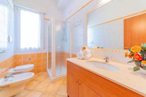 ein Badezimmer mit einem Waschbecken, einem WC und einem Spiegel in der Unterkunft Residence Promenade in Cattolica