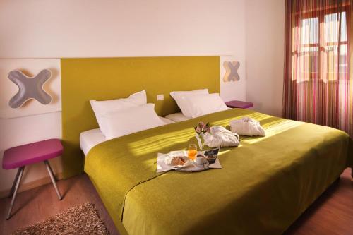 een slaapkamer met een groot geel bed met twee poppen erop bij VELANERA Hotel & Restaurant in Medulin