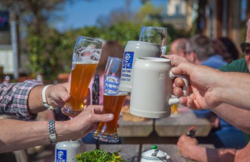 a group of people holding up glasses of beer at Hotel Almwirt in Haar
