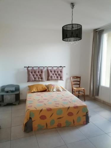 une chambre avec un grand lit et un lustre dans l'établissement Chez Lydie, à Cessenon