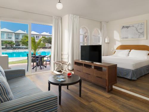 een slaapkamer met een bed en een woonkamer met een tv bij H10 Ocean Suites in Corralejo