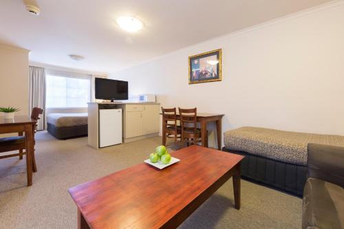 a living room with a room with a couch and a table at Canberra Parklands Central Apartment Hotel Official in Canberra