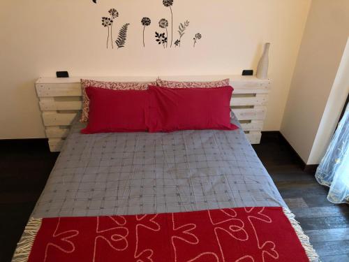 a bedroom with a bed with red pillows at Benvenuti a casa EMAGAL a due passi dal fiume in Sesto Calende