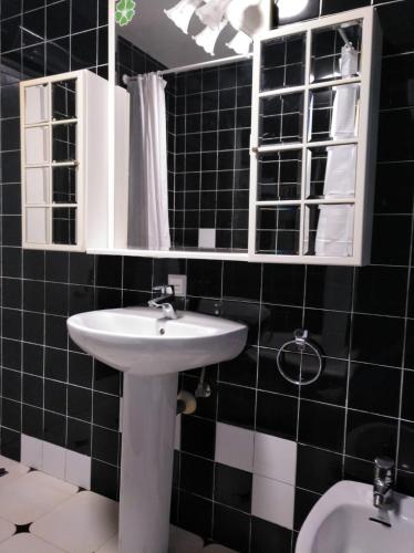 a black tiled bathroom with a sink and a toilet at apartamento buenavista in Luarca