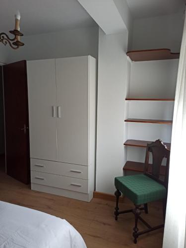 a bedroom with a bed and a chair and a closet at apartamento buenavista in Luarca