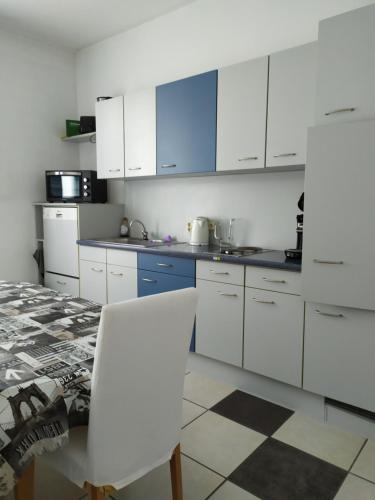 a kitchen with white cabinets and a table and a white chair at Monteurzimmer EZ GROß in Frankfurt/Oder