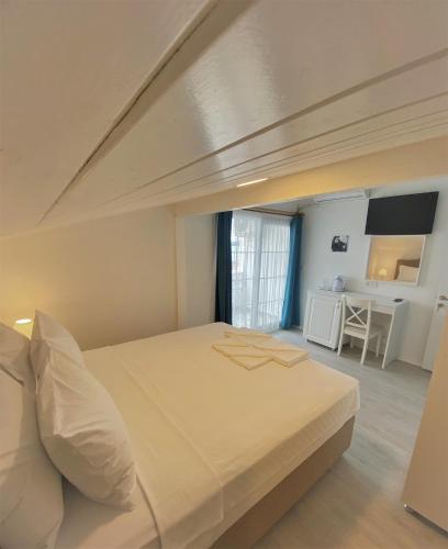 a bedroom with a large bed and a desk at Cunda Kordon Otel in Ayvalık