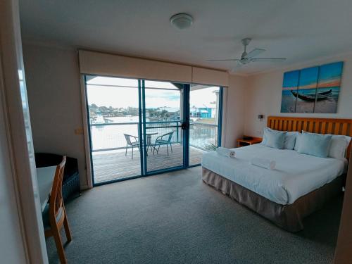 a bedroom with a bed and a view of a balcony at The View - Captains Cove Waterfront Resort in Paynesville