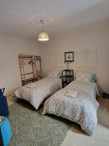 a bedroom with two beds and a chandelier at Ancient Stone 'Casa Rosa'- Sea and Mountain View Tranquil Borgo in Tavenna
