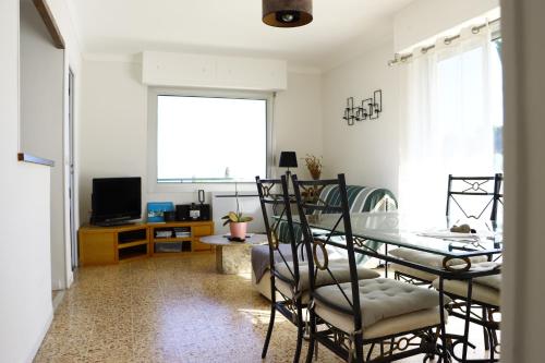 a dining room with a table and chairs and a television at Résidence Stella Maris in Antibes