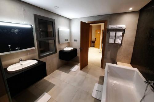 La salle de bains est pourvue de 2 lavabos, d'une baignoire et d'un miroir. dans l'établissement Zephyr Mazagan, à El Jadida