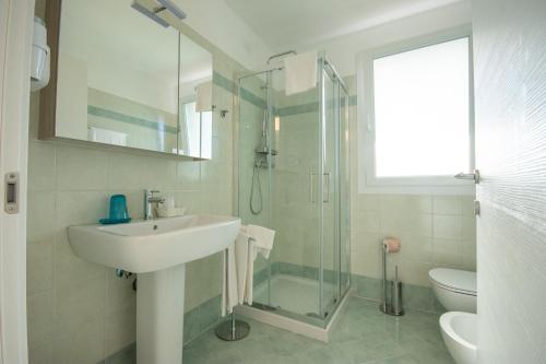 a bathroom with a sink and a glass shower at Hotel & Apartments Eldorado in Grado