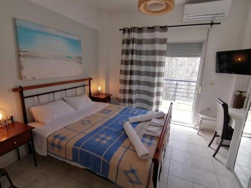 a bedroom with a bed and a desk and a window at Kassandros Studios - Hanioti Halkidiki in Hanioti