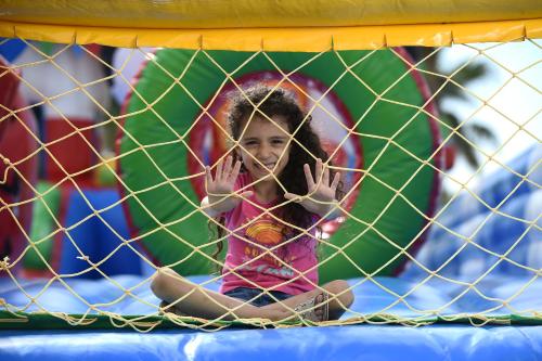 a little girl sitting inside of a net at Sealine Beach, a Murwab Resort in Mesaieed