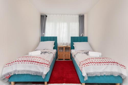 2 camas en una habitación con alfombra roja en Seaside Apartment Gdynia Redłowo by Renters en Gdynia
