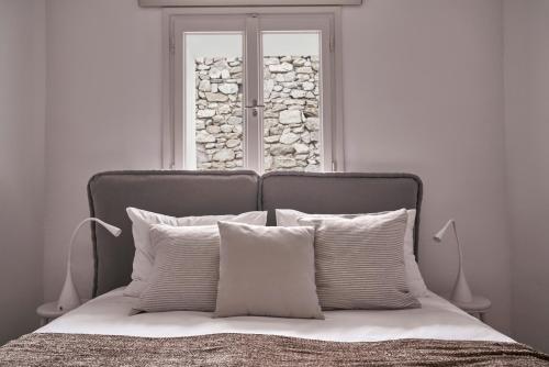 a bed with white pillows in front of a window at Casa Bo Private Pool in Mýkonos City