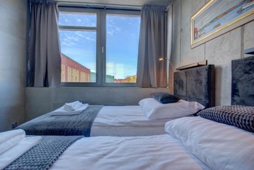two beds in a room with a window at HelApart - Loft in Hel