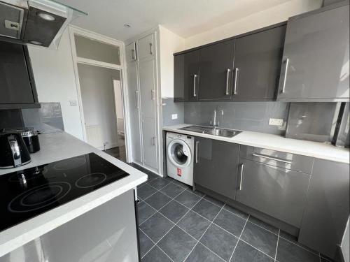 uma cozinha com armários pretos e uma máquina de lavar e secar roupa em Bright and spacious 2 bedroom apartment em Sutton