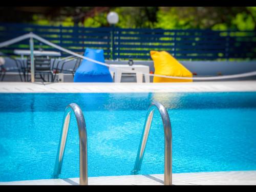 a swimming pool with blue water and blue chairs at Thassian Riviera Hotel in Skala Prinou