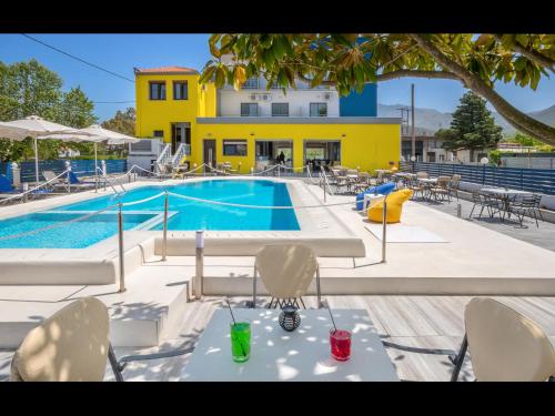 ein Pool mit Tischen und Stühlen und ein gelbes Gebäude in der Unterkunft Thassian Riviera Hotel in Skala Prinos