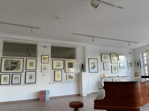 a room with pictures on a wall with a piano at Waldwerk Wurlgrund Lychen in Lychen