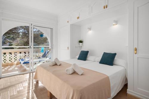 a white bedroom with two beds and a balcony at Punta Prima Apartments in Punta Prima