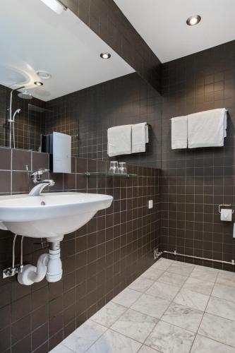 a bathroom with a white sink and brown tiles at Ibis Styles Stockholm Odenplan in Stockholm