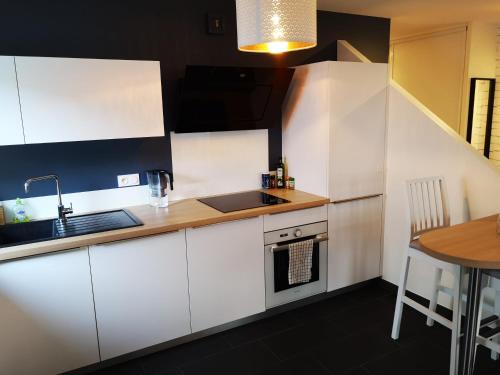 a kitchen with white cabinets and a sink and a table at Appartement T3 centre ville Mabilais au calme. in Rennes