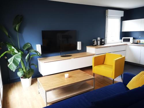 uma sala de estar com uma televisão e uma cadeira amarela em Appartement T3 centre ville Mabilais au calme. em Rennes