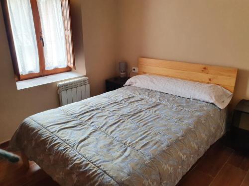 a bedroom with a bed with a wooden headboard and a window at El Castillo de Moratinos in Moratinos