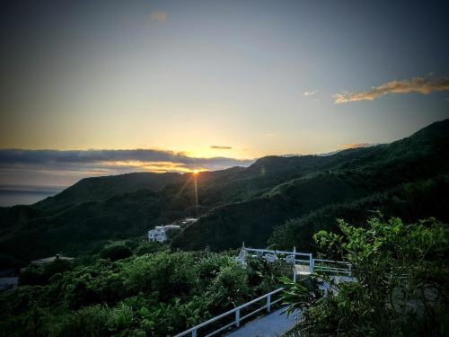 a view of the sun setting over a mountain at A Promised Land BnB in Jiufen