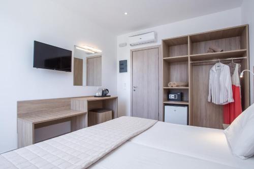 a bedroom with a white bed and a tv at Stamos All Inclusive in Faliraki