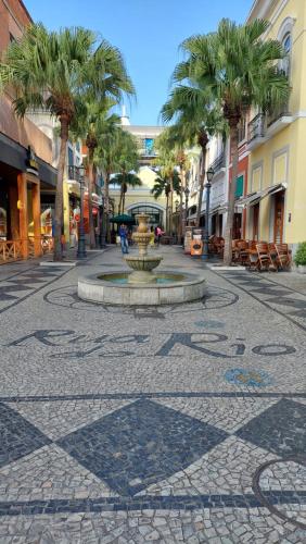 a street with a fountain in the middle of a street with palm trees at ibis budget Rio de Janeiro Nova America in Rio de Janeiro