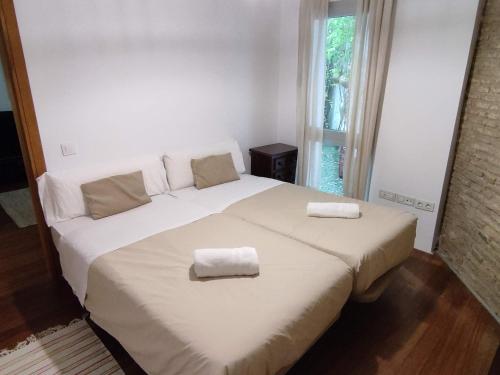 a bedroom with a large white bed with two towels on it at Apartamento Un Jardin en la Alfalfa - Kainga Homes in Seville