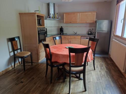 a kitchen with a red table and chairs in it at LES GÎTES CELTIQUES DU PÈRE NICOLAS in Plumeliau Bieuzy