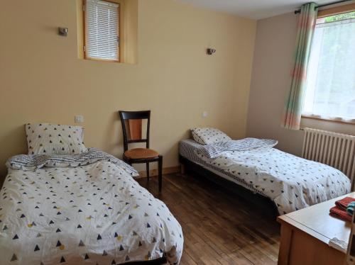 1 dormitorio con 2 camas individuales y 1 silla en LES GÎTES CELTIQUES DU PÈRE NICOLAS, en Pluméliau