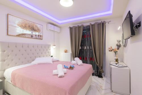 a bedroom with a large bed with pink sheets and a tv at Alkeos Suite in Zakynthos Town