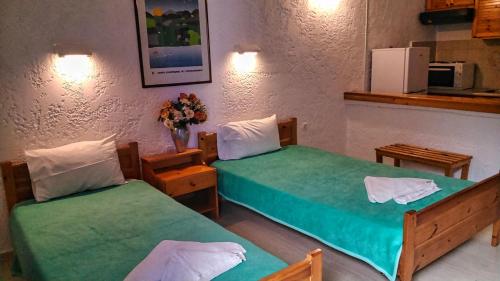 2 Betten in einem Zimmer mit grüner Bettwäsche in der Unterkunft Fotula Studios in Agia Pelagia