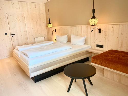 a bedroom with a bed and a stool and a table at Forstnerwirt hotel | stubn | biergarten in Rottenburg an der Laaber