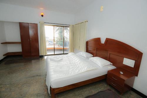 a bedroom with a bed and a large window at SAIKUSHI BEACH RESORT in Kundapur