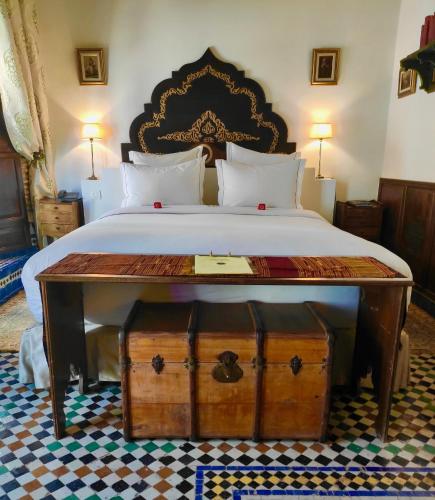 a bedroom with a bed with a large bed with a table at Riad Le Calife in Fès