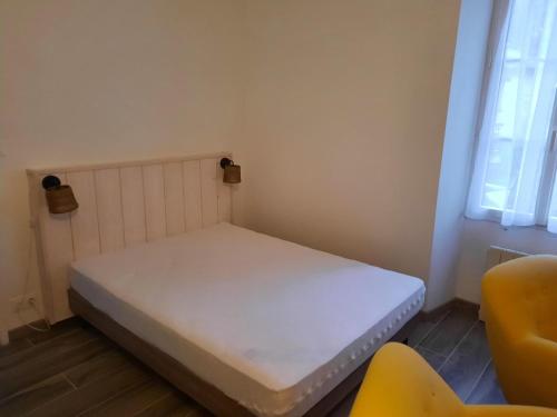 ein kleines Bett in einem Zimmer mit einem gelben Stuhl in der Unterkunft Gîtes de la mousseterie in Échiré