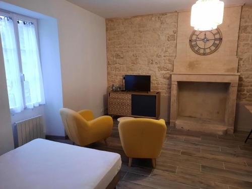 a living room with a bed and chairs and a fireplace at Gîtes de la mousseterie in Échiré