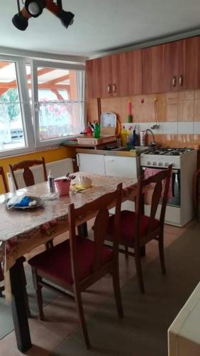 a kitchen with a wooden table and chairs and a table and a stove at Nagymama Házikója in Tiszasas