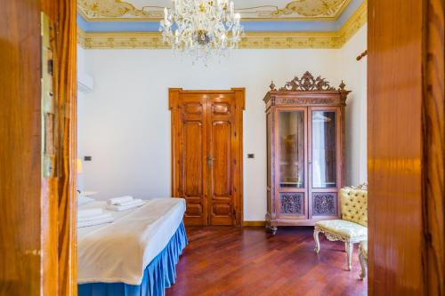 a bedroom with a bed and a chandelier at Palazzo Montalbano in Scicli