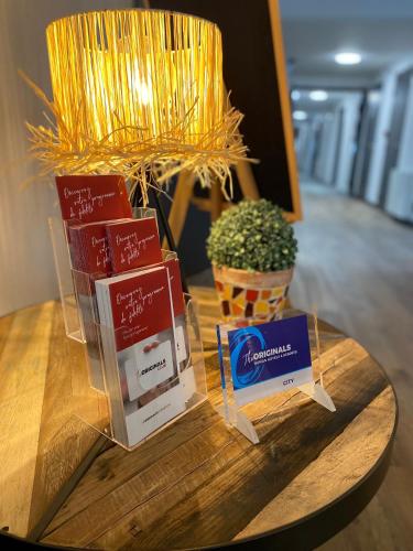 a table topped with boxes on a table with a plant at The Originals City, Angers Sud, Le Village 49 in Les Ponts-de-Cé