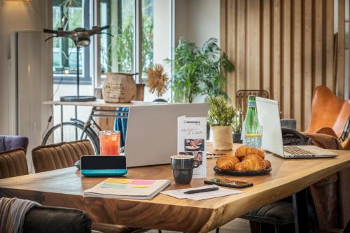 an office table with a laptop and bread on it at The Originals City, Angers Sud, Le Village 49 in Les Ponts-de-Cé